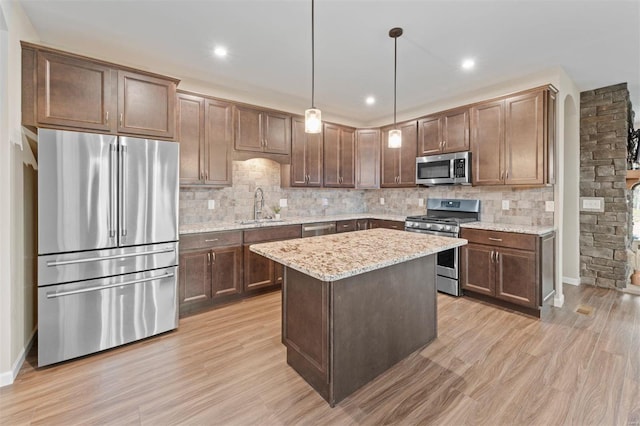 kitchen with tasteful backsplash, light stone countertops, stainless steel appliances, light wood-style floors, and a sink