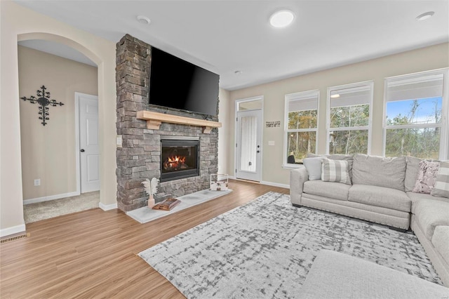 living room featuring baseboards, a fireplace, visible vents, and wood finished floors