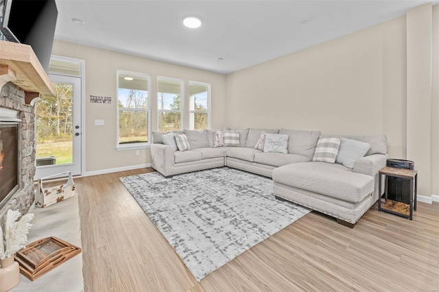 living area featuring a fireplace, baseboards, and wood finished floors