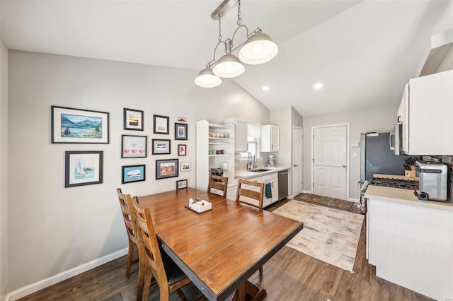 dining area featuring dark hardwood / wood-style flooring, sink, and vaulted ceiling