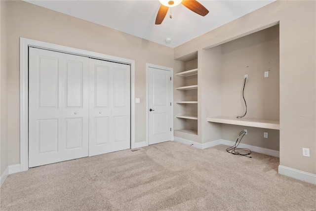 unfurnished bedroom with ceiling fan, built in desk, and light carpet