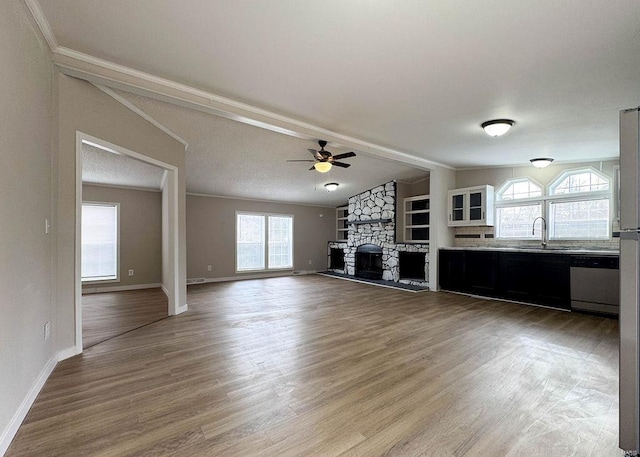 unfurnished living room with sink, a stone fireplace, plenty of natural light, and lofted ceiling with beams