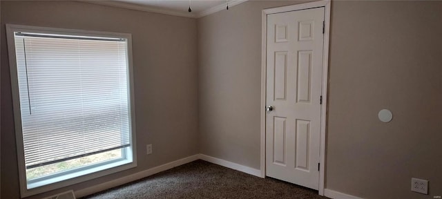 spare room featuring dark carpet and crown molding