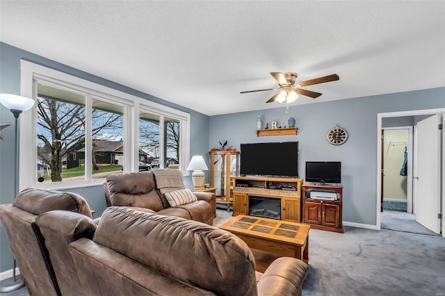 carpeted living room featuring ceiling fan and a textured ceiling