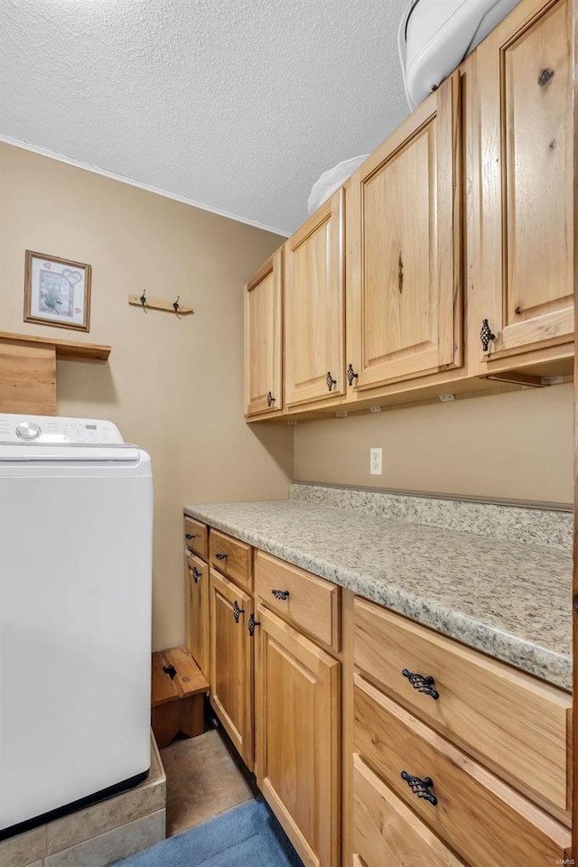 washroom featuring cabinets, a textured ceiling, and washer / clothes dryer