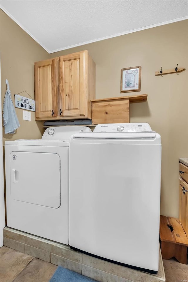 washroom featuring washing machine and clothes dryer, crown molding, and cabinets