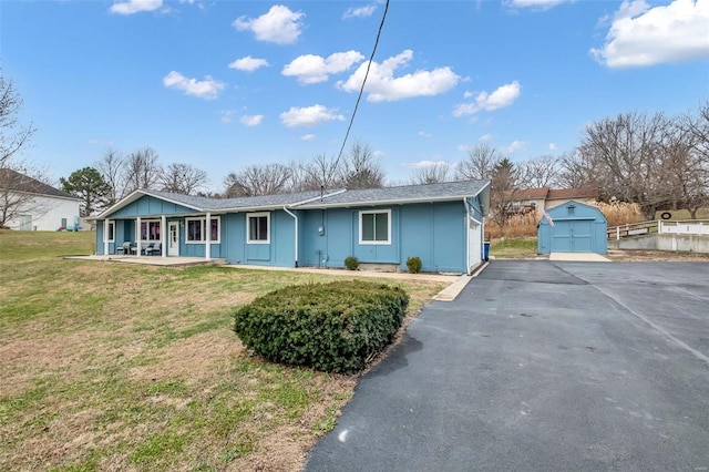 ranch-style house featuring a garage, a porch, a storage shed, and a front lawn