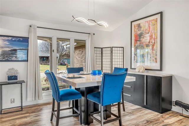 dining space with light hardwood / wood-style floors, a wealth of natural light, and lofted ceiling