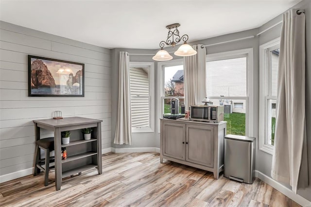 dining area with light hardwood / wood-style floors and wood walls