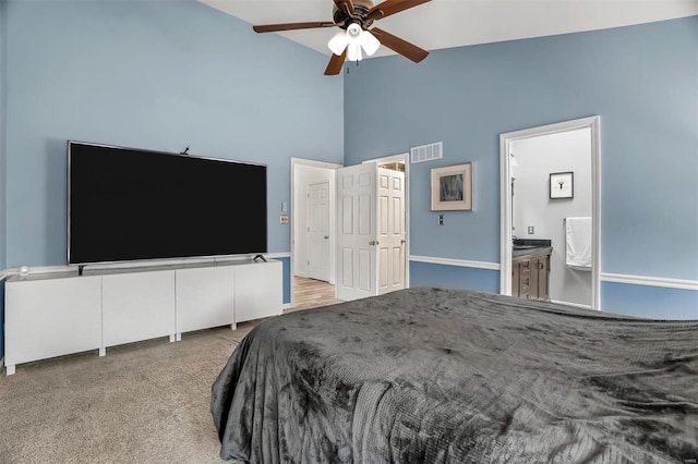 bedroom featuring ceiling fan, high vaulted ceiling, light carpet, and ensuite bath