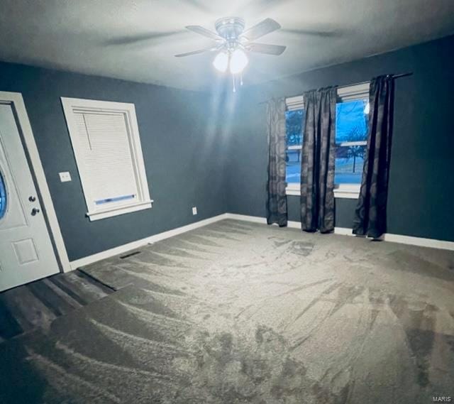 spare room with a healthy amount of sunlight, ceiling fan, and dark carpet