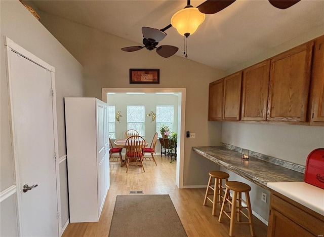 kitchen featuring ceiling fan, vaulted ceiling, and light wood-type flooring