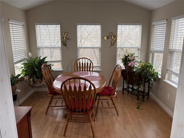 dining area with a healthy amount of sunlight, light hardwood / wood-style floors, and vaulted ceiling