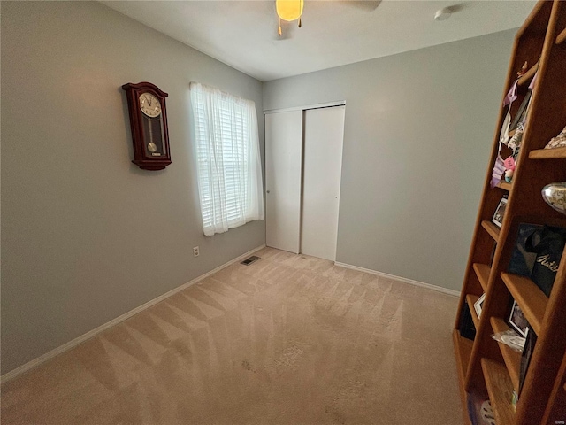 unfurnished bedroom featuring ceiling fan, a closet, and light carpet