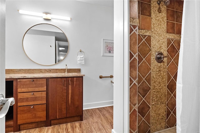 bathroom featuring vanity, wood-type flooring, and tiled shower