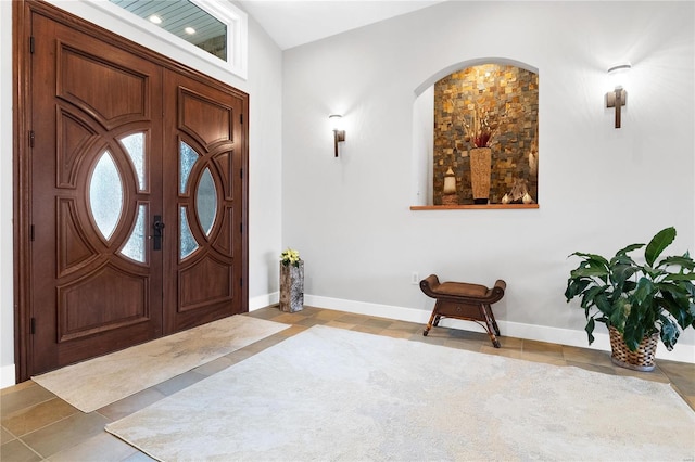 foyer entrance featuring light tile patterned flooring and vaulted ceiling