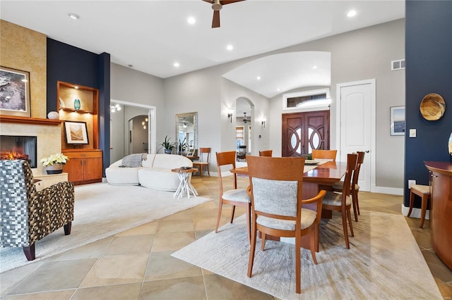 dining room featuring light tile patterned floors, a large fireplace, ceiling fan, and built in shelves