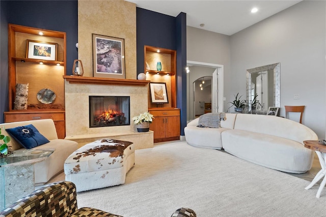 living room featuring light carpet, built in shelves, and a premium fireplace