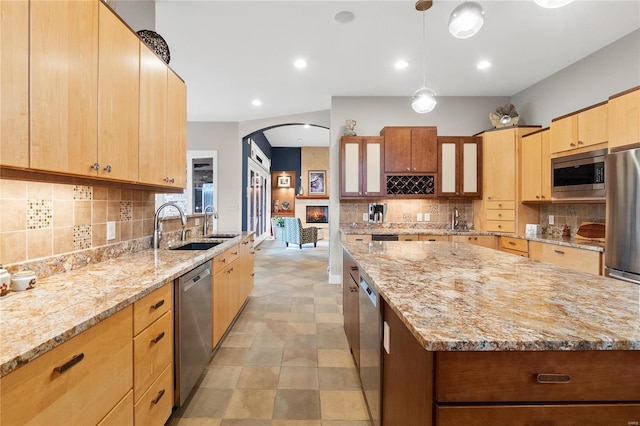 kitchen with hanging light fixtures, a kitchen island, stainless steel appliances, and sink