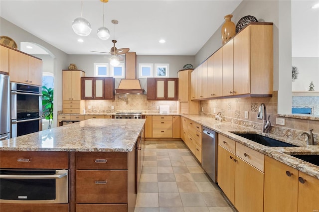 kitchen featuring light stone countertops, a kitchen island, stainless steel appliances, and ceiling fan