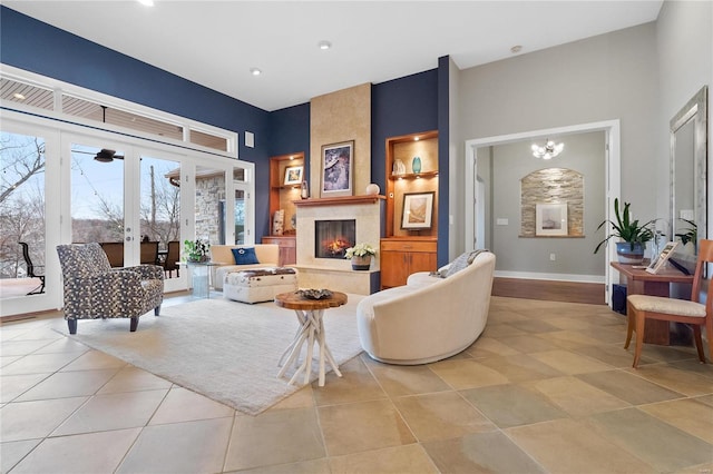 living room featuring a chandelier, light tile patterned flooring, a high end fireplace, and french doors