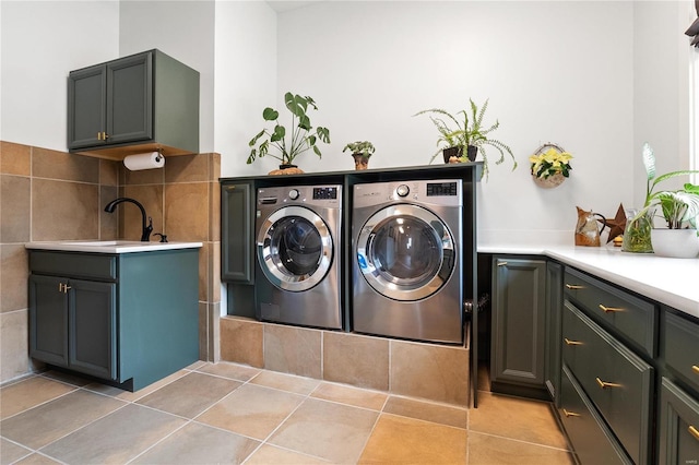 laundry area featuring washer and dryer, light tile patterned flooring, cabinets, and sink