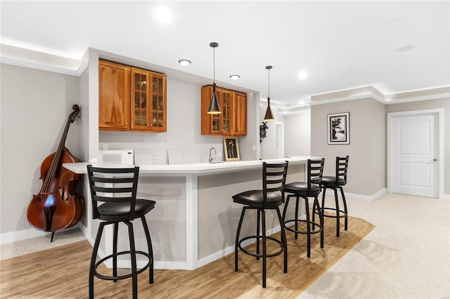 kitchen featuring a kitchen bar, sink, pendant lighting, and light hardwood / wood-style flooring