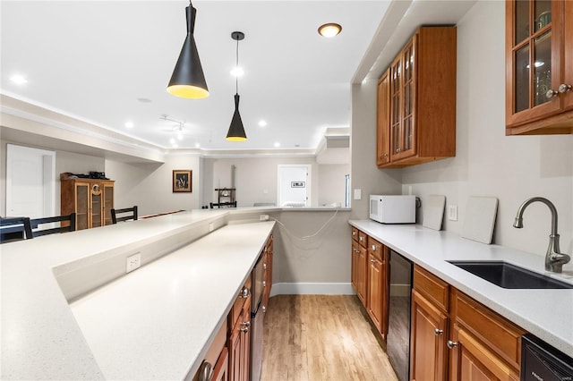 kitchen with dishwasher, sink, decorative light fixtures, and light wood-type flooring