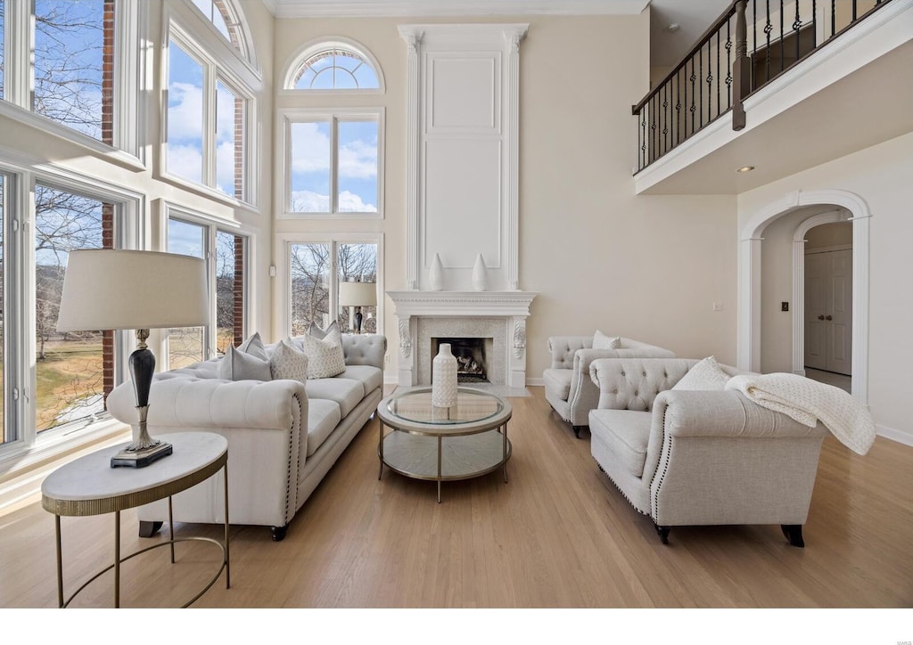 living room with a high ceiling, plenty of natural light, a fireplace, and light wood-type flooring