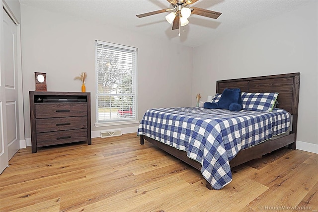 bedroom with ceiling fan, light hardwood / wood-style floors, and a textured ceiling