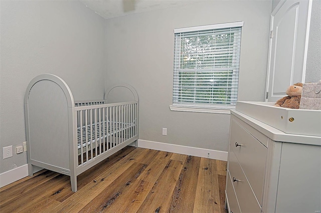 bedroom featuring light hardwood / wood-style flooring, a crib, sink, and multiple windows