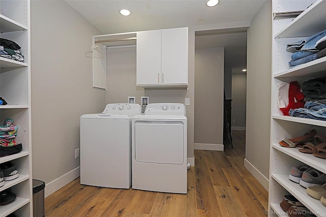 clothes washing area featuring cabinets, light wood-type flooring, and washer and dryer