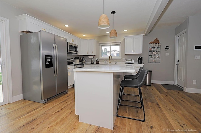 kitchen with a center island, white cabinets, pendant lighting, and appliances with stainless steel finishes