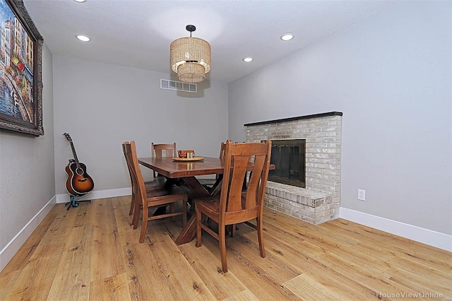 dining room featuring light hardwood / wood-style flooring and a brick fireplace