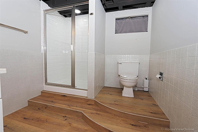 bathroom with hardwood / wood-style floors, an enclosed shower, tile walls, and toilet