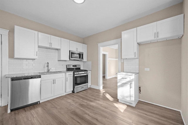 kitchen with light stone counters, white cabinetry, sink, and appliances with stainless steel finishes