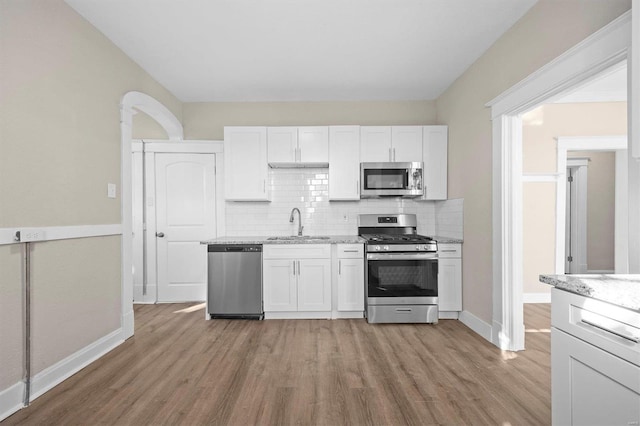 kitchen featuring sink, decorative backsplash, light wood-type flooring, white cabinetry, and stainless steel appliances