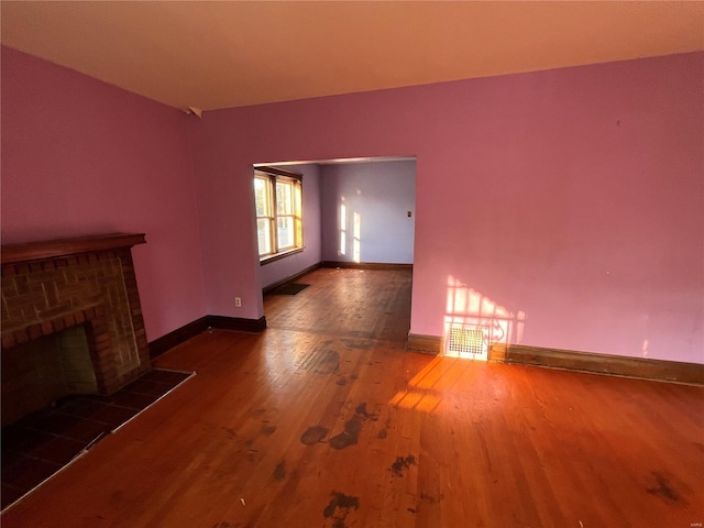 unfurnished living room featuring dark hardwood / wood-style floors and a brick fireplace