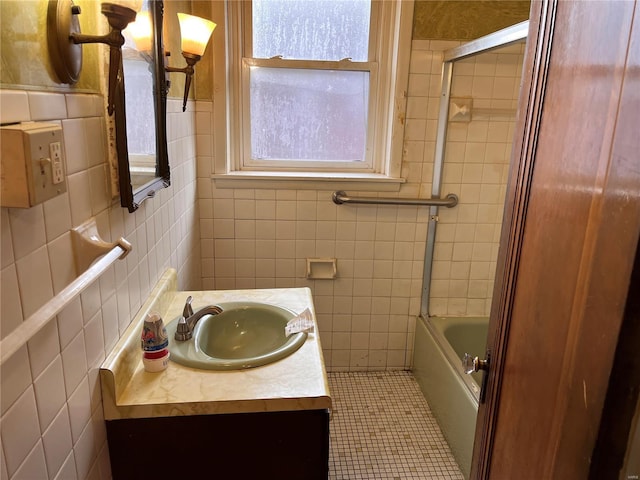 bathroom featuring tile patterned floors, vanity, tile walls, and combined bath / shower with glass door