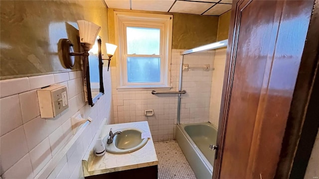 bathroom with tile patterned floors, vanity, enclosed tub / shower combo, and tile walls