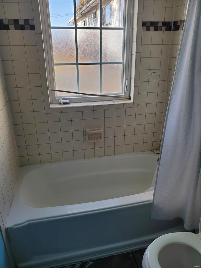 bathroom with shower / bath combination with curtain and toilet