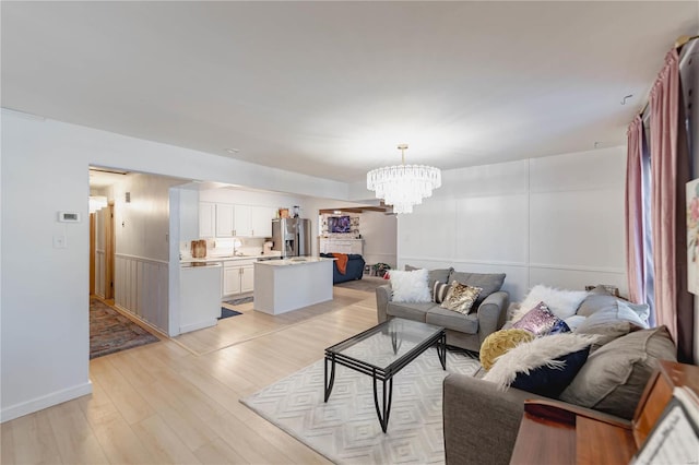 living room with sink, light hardwood / wood-style floors, and an inviting chandelier