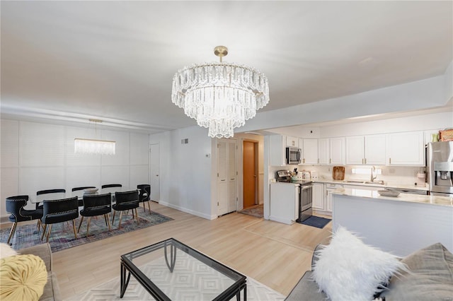 living room featuring light hardwood / wood-style floors, sink, and a chandelier