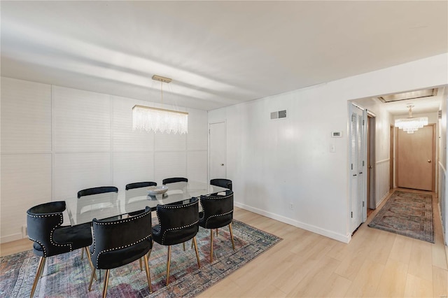 dining area featuring light hardwood / wood-style floors and a chandelier