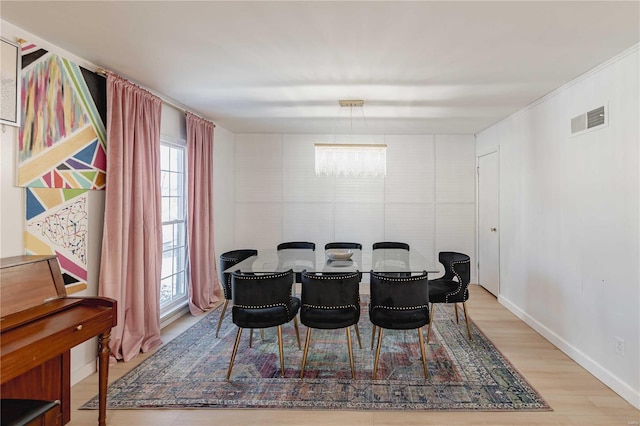 dining space with hardwood / wood-style floors and a notable chandelier