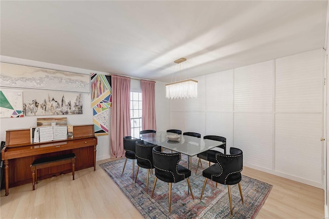 dining space featuring light wood-type flooring and a notable chandelier