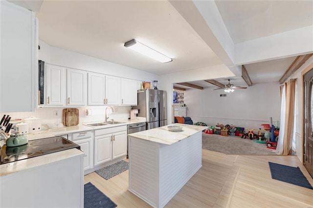 kitchen with sink, a kitchen island, white cabinetry, and appliances with stainless steel finishes