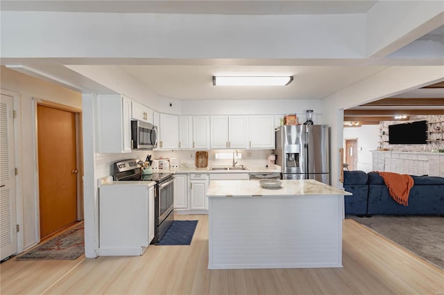 kitchen featuring sink, white cabinets, light wood-type flooring, decorative backsplash, and stainless steel appliances