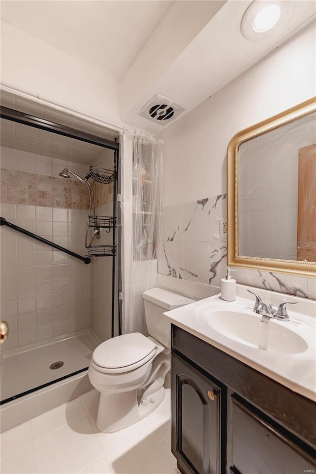 bathroom featuring tile patterned flooring, vanity, tile walls, toilet, and tiled shower