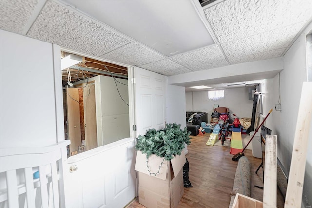 basement featuring wood-type flooring and a drop ceiling